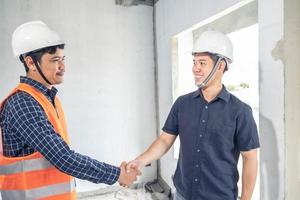 pareja asiática revisando la casa con el capataz de ingeniería inspección de la casa construcción de la casa caminar inspección de la casa con mirar y señalar la construcción para verificar la construcción de la casa en el lugar de trabajo hasta la construcción 2021 foto