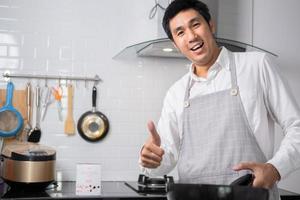 Asian chef fried eggs on pan to thai food in kitchen on gas stove The oil in pan boiling.Eggs and pork cooked. before serving to happy family to eat togetherness in home photo