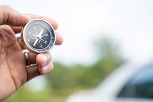 Man hand holding compass on city and car blurred background Using wallpaper or background travel or navigator image. photo