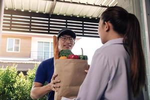 Delivery of an asian man handling a bag of food to a female customer at the door. photo