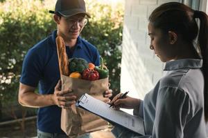 Asian woman is checking the product and signing the receipt on the order receipt through the online supermarket's home store. photo