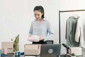 Asian entrepreneur is preparing her clothes that can be sold in paper boxes for delivery to customers. photo