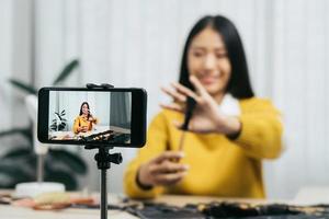 Asian teenage girls doing makeup vlogs and using a video mobile camera to record vlogs and publish them online at home. photo