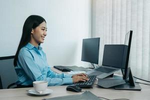 mujer de negocios que trabaja en un monitor profesional de computadora de escritorio y se sienta en su escritorio de oficina y trabaja en un nuevo programa de software. foto