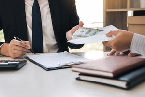 Entrepreneurs are signing a contract about business under fraud while colleagues give money in an envelope. photo