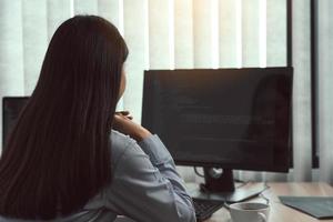 desarrolladores de software de mujeres asiáticas sentadas frente a computadoras mirando códigos de computadora en la pantalla. foto