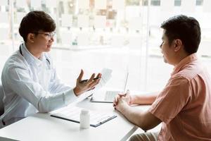 médico hablando de la lista de antecedentes del paciente en el bloc de notas y hablando con el paciente sobre la medicación y el tratamiento. foto