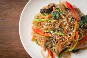 japchae or stir-fried Korean vermicelli noodles with vegetables and pork topped with white sesame photo