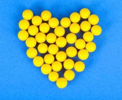pequeñas píldoras amarillas redondas farmacéuticas médicas, vitaminas, medicamentos, antibióticos en forma de corazón foto