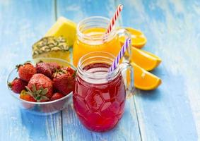 Fresh pineapple and strawberry smoothie in glasses with fruits on a blue wooden rustic background photo