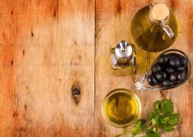 Olive oil with fresh herbs and Black olives  on wooden photo