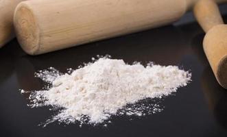 The white flour with a rolling pin on black