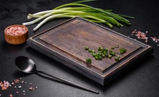 Black metal spoon and rectangular cutting board on black concrete background photo