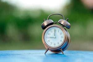 Golden alarm clock picture placed on a blue table, green background Punctual concept With copy space photo