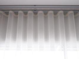 White sheer curtains with translucent fabric hanging on window photo