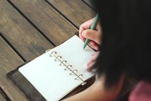 mujer escribiendo meta en un cuaderno en el espacio al aire libre de la cafetería foto