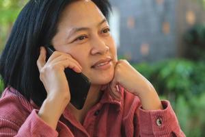 asian woman talking with mobile at coffee shop photo