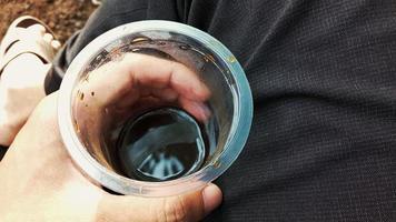 Hand holding retail coffee in cheap plastic cup. photo