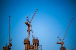 Construction crane is working building in the blue sky. photo