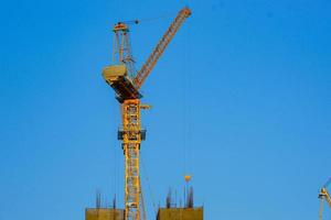 Construction crane is working building in the blue sky. photo