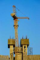 Construction crane is working building in the blue sky. photo