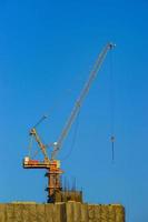 Construction crane is working building in the blue sky. photo