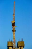 Construction crane is working building in the blue sky. photo