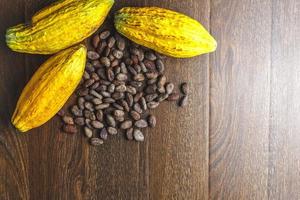 vainas de cacao frescas y granos de cacao sobre fondo de madera foto