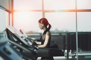 Asian sport woman running on treadmill in fitness club. Cardio workout. Healthy lifestyle, guy training in gym. Sport running concept photo