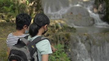 Female nature conservationist giving information to a teenage girl about ecosystem of waterfall.