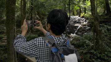 kvinnlig backpacker tycker om att ta bilder och videoinspelningar med mobil smartphone under vandringstur i skogen. video