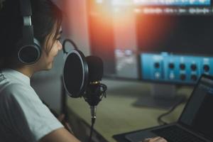 Asian woman wearing headphones and sing a song record sound with a microphone and use computer recording music program. sound engineer woman record music. photo