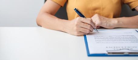 Woman signing on contract documents after reading, hand holding pen and approve on business report. Contract agreement, partnership and deal concepts photo