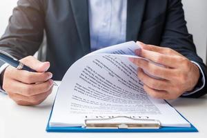 Businessman signing on contract documents after reading, man holding pen and approve on business report. Contract agreement, partnership and deal concepts photo