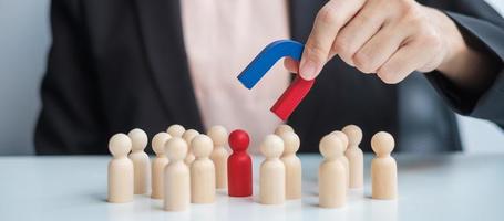 Business woman hand holding magnet and pulling man wooden figure from the crowd employee. Business, Human resource management, Recruitment, Teamwork, strategy, toxic people and leadership Concepts photo