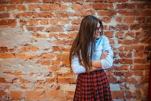 Beautiful young woman stands near the old brick wall. Youth styl photo