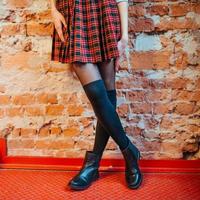 Sexy legs of a girl in  skirt and black boots photo