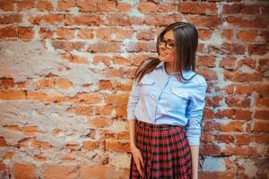 hermosa joven se encuentra cerca de la vieja pared de ladrillos. estilo juvenil foto