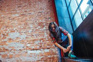 Beautiful young woman stands near the old brick wall. Youth styl photo