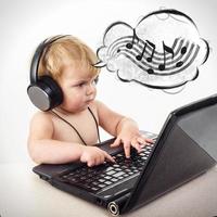 Cute little girl is sitting at table with her black laptop, isol photo