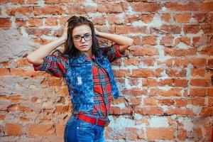 Beautiful young woman stands near the old brick wall. Youth styl photo