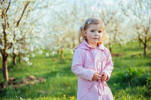 Little baby girl 3 years, that runs between flowering trees outd photo