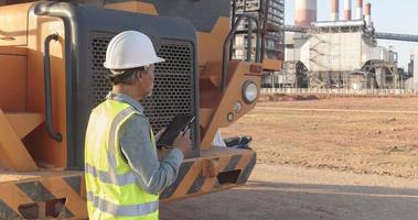 A senior engineer uses a tablet on a construction site against a clear sky on a sunny day. photo