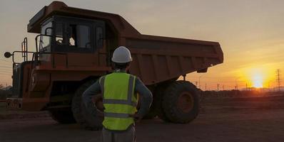 Los conductores de camiones de carbón en la mina de carbón se paran para ver la puesta de sol. foto