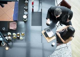 Two attractive Caucasian businesspeople colleagues sitting at the coffee bar using a computer tablet talking informal discussion at coffee break zone. Top view Businesspeople discussion planning photo