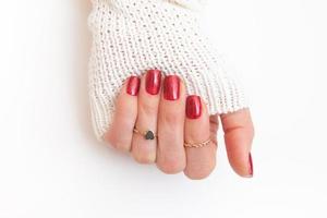 esmalte de gel de manicura de color rojo con destellos en la mano femenina con anillos foto