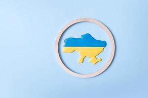 Map of Ukraine in yellow-blue colors of the Ukrainian flag in a round wooden frame. Ukraine sky protection concept photo