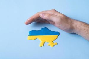 Mans hand over the shape of the map of Ukraine in yellow and blue colors of the national flag photo