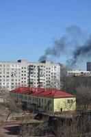 There is black smoke from a rocket or bomb explosion in a city during a war photo