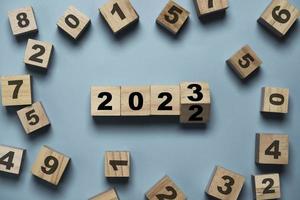 voltear de 2022 a 2023 en un cubo de bloque de madera con otro número para preparar el cambio de año nuevo y comenzar un nuevo concepto de estrategia de objetivo comercial. foto